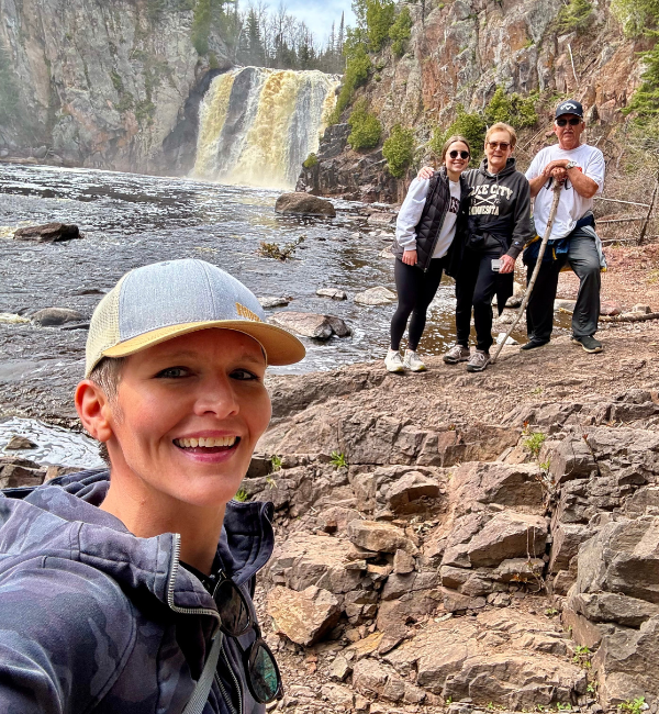Melissa, happy human personal trainer, with family and friends at a waterfall